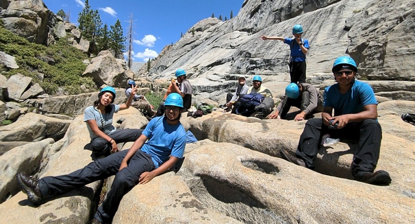 a group of backpacking students rest on rocks on an expedition with outward bound